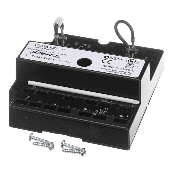 A black rectangular electronic component with labeled terminals, two attached wires, a white rod, and two screws placed in front.