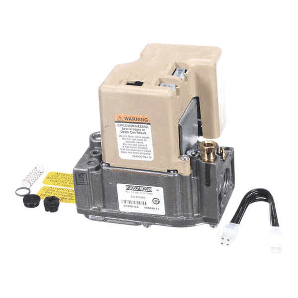 A mechanical component with a beige plastic cover, metal base, warning label, and several small accessories including a spring, caps, and a black cable with a white connector.
