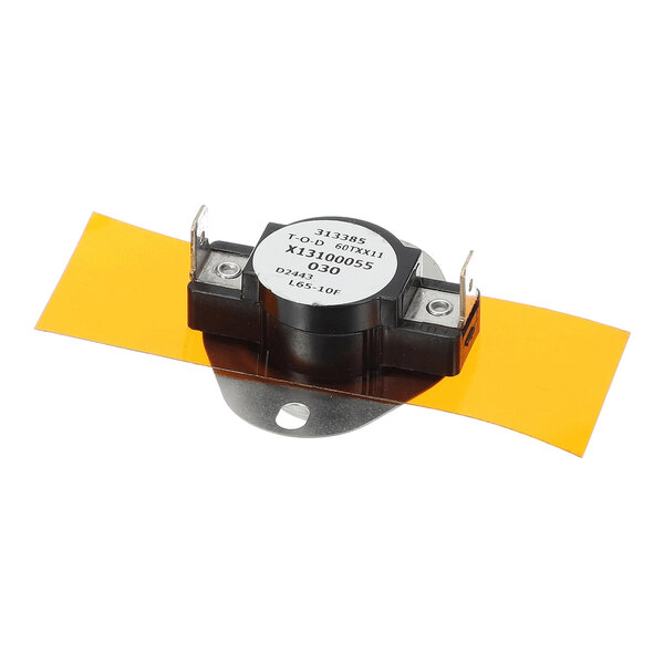 A small round electronic component with two metal terminals, mounted on a metal bracket and placed on an orange rectangular sheet.