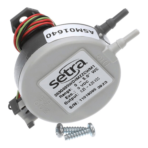 A round electronic sensor device with wires, two hose connectors, a label displaying technical specifications, and two screws placed in front.