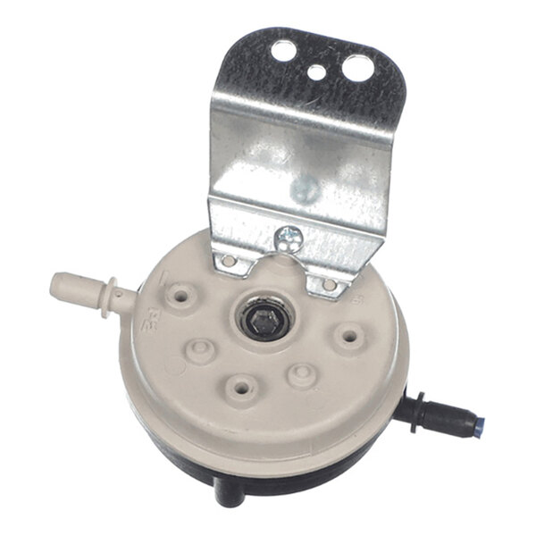 A round, beige plastic component with multiple small protrusions, two hose connectors on opposite sides, and a metal mounting bracket attached to the top.
