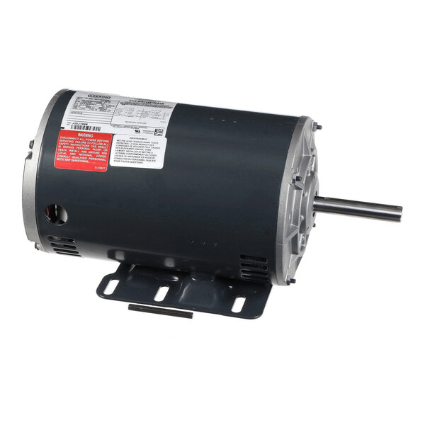A cylindrical electric motor with a metal mounting base and a protruding shaft, featuring several labels and warning stickers on its surface.