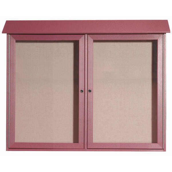 An Aarco rosewood outdoor message center with vinyl tackboard behind two pink plastic doors.