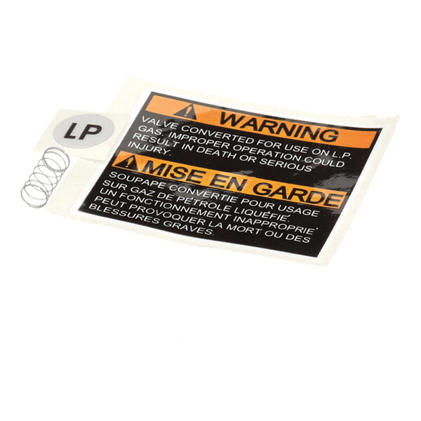 A small kit containing a warning label with English and French text, a circular sticker labeled 'LP,' and a small metal spring.