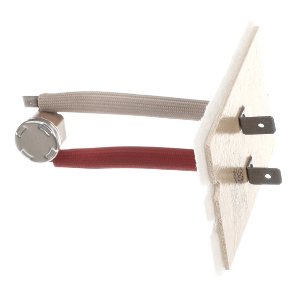 A small electronic component with two wires (one red, one gray) connected to a metal cylindrical part and mounted on a rectangular board with two metal prongs.