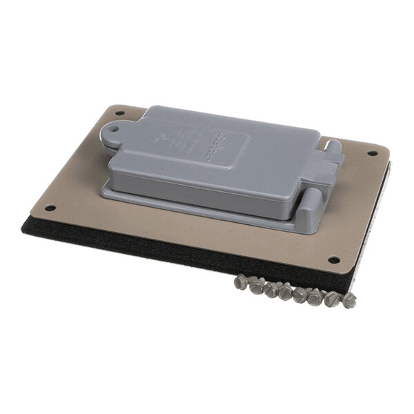 A rectangular metal plate with a gray hinged cover, a black gasket layer, and several screws placed beside it.
