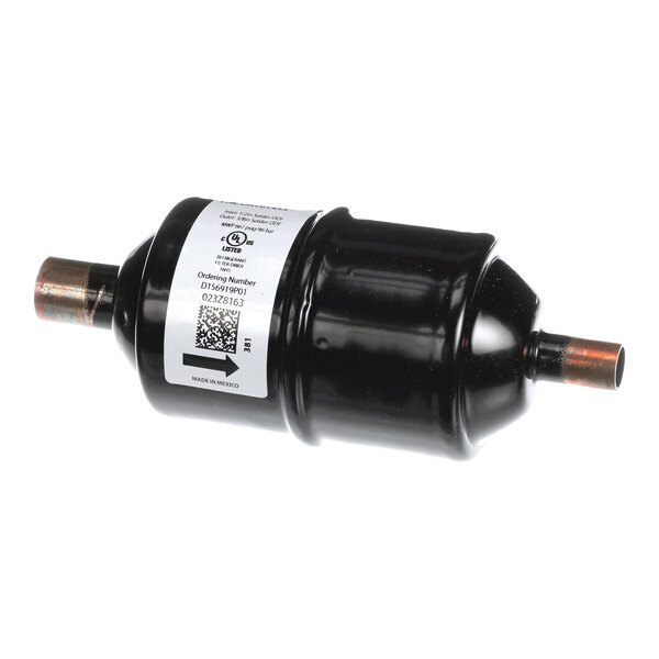 A black cylindrical component with copper pipe fittings on both ends and a white label attached to its body.