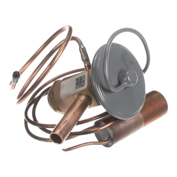 A metal component with copper tubing, a cylindrical valve body, and a round gray cap, likely part of a mechanical or HVAC system.