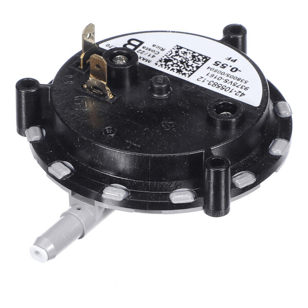 A round black plastic component with a white label, metal terminal, and a gray hose connector protruding from the side.
