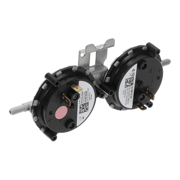 Two round black components with labels, metal mounting bracket, and protruding metal and plastic connectors, likely part of an HVAC system.
