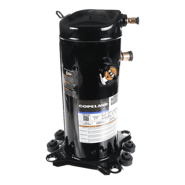 A black cylindrical mechanical component with attached labels, copper pipe fittings, and a mounting base with four rubber feet.