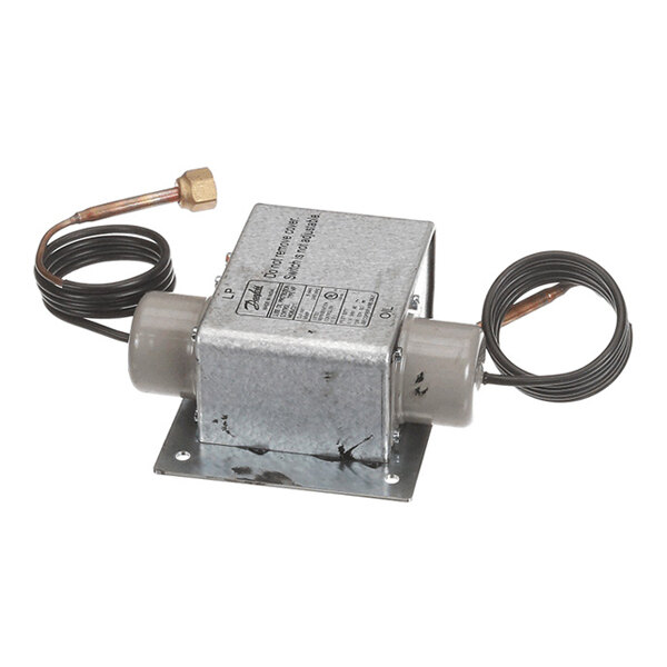 A metallic box-shaped device with two cylindrical extensions, coiled wires, and a brass fitting on one end, mounted on a flat metal base.