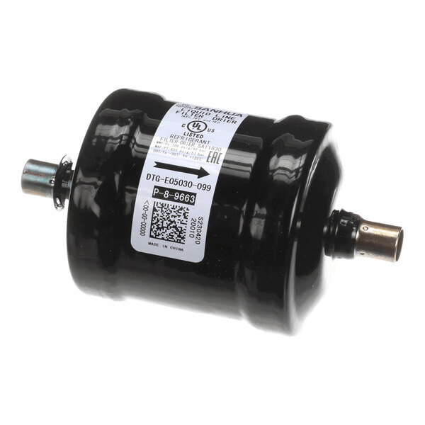A cylindrical black metal component with two pipe connections and a white label featuring text and a QR code.