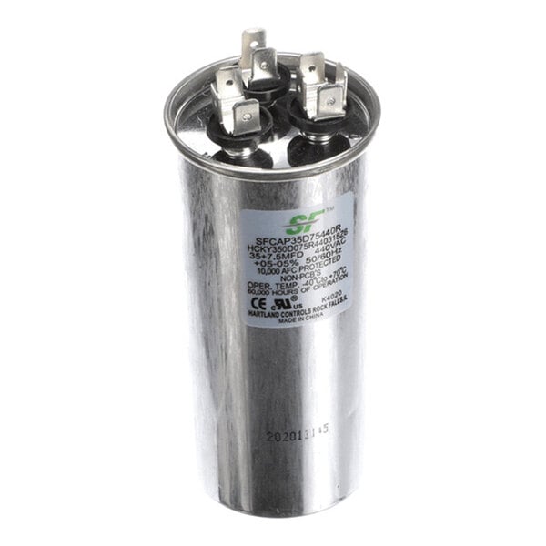A cylindrical metallic capacitor with three electrical terminals on top and a label displaying technical specifications on the side.