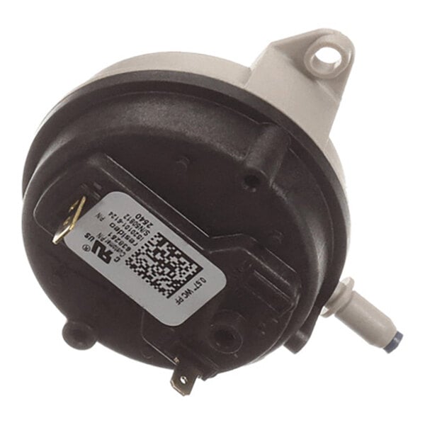 A round, black and gray component with a mounting bracket, electrical terminals, a label with a QR code, and a hose connection port.