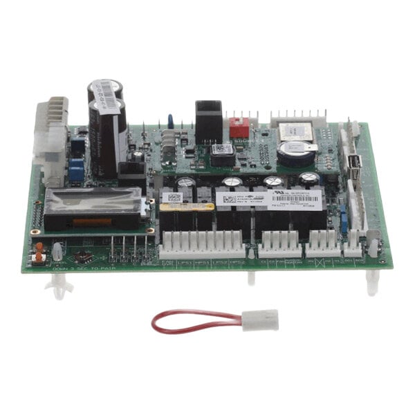 A green electronic circuit board with various components, connectors, and a small wire harness placed in front of it.