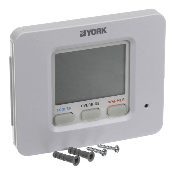 A rectangular digital thermostat with three labeled buttons (Cooler, Override, Warmer), a display screen, and two screws with wall anchors placed in front of it.