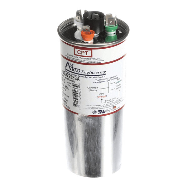 A cylindrical metallic component with three colored terminals (black, orange, and green) on top and a label with technical specifications on the side.