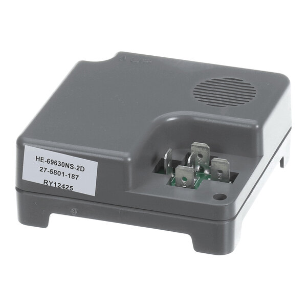 A gray electronic component with a vented area, several metal connectors, and a label with alphanumeric codes.