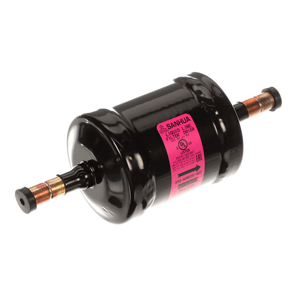 A cylindrical black metal component with copper pipe fittings on both ends and a pink label in the center.