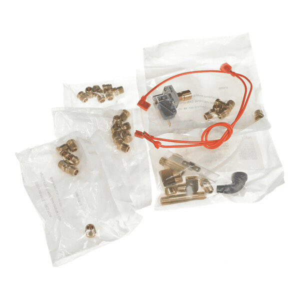 Several small brass fittings and components, along with a red wire and a black plastic piece, are packaged in clear plastic bags.