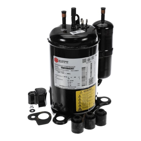 A black cylindrical mechanical component with attached pipes, electrical terminals, and several mounting accessories, likely part of a refrigeration or HVAC system.