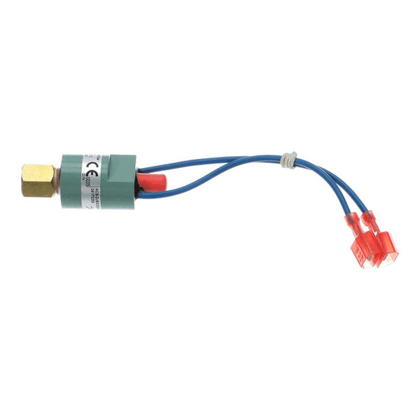 A small cylindrical device with a brass fitting on one end, a green body with a label, and two blue wires ending in red connectors.