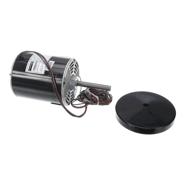 A cylindrical electric motor with attached wires and a separate round black cover placed beside it.