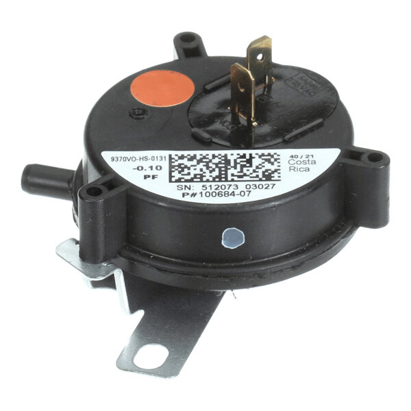 A round black pressure switch with two metal terminals, a mounting bracket, and a label with a barcode and technical information.