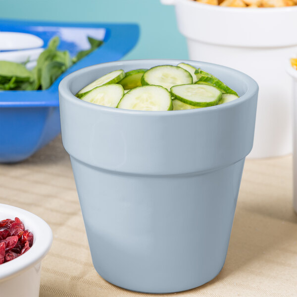 A Tablecraft gray cast aluminum round condiment bowl with cucumbers and other food.