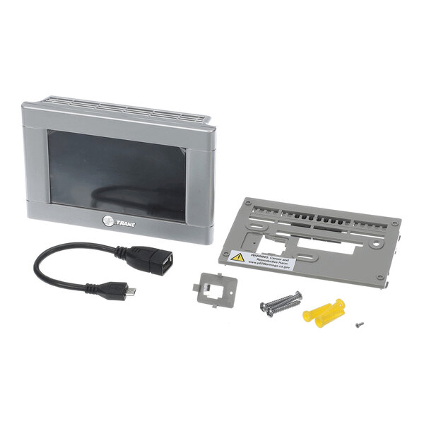 A gray electronic control panel with a display screen, a mounting plate, a short USB cable, screws, wall anchors, and a small metal bracket arranged on a white surface.