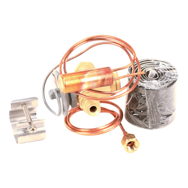 A collection of metal components including a coiled copper tube, a brass fitting, a metal clamp, and a roll of black material.