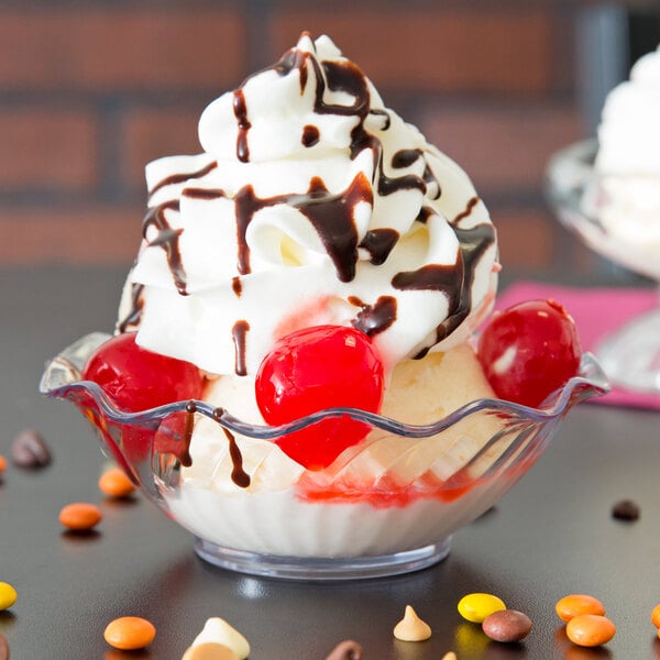 A Carlisle clear tulip berry dish filled with a dessert topped with whipped cream and cherries.