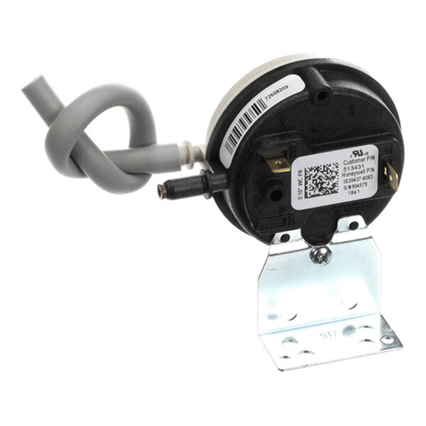 A round black and silver device with a metal mounting bracket, a gray coiled tube, and labeled stickers on its surface.