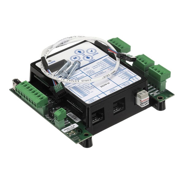 An electronic circuit board with multiple green terminal blocks, a central black module with a label, a white cable, and two screws placed on top.