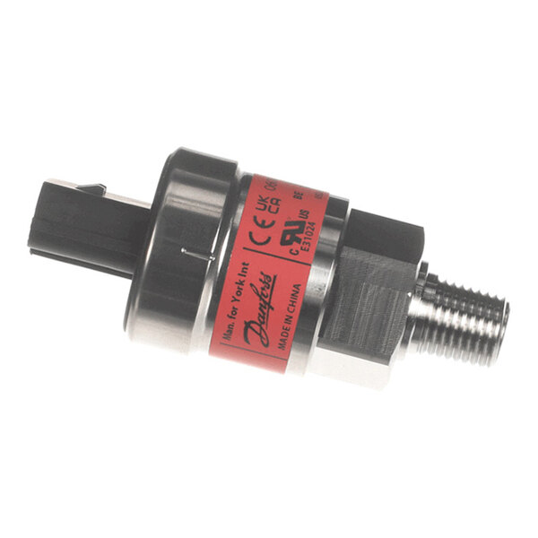 A small cylindrical metal and plastic component with a threaded end and an electrical connector, featuring a red label with text and certification markings.