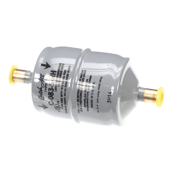 A cylindrical metallic component with two capped pipe fittings and printed labeling on its surface.