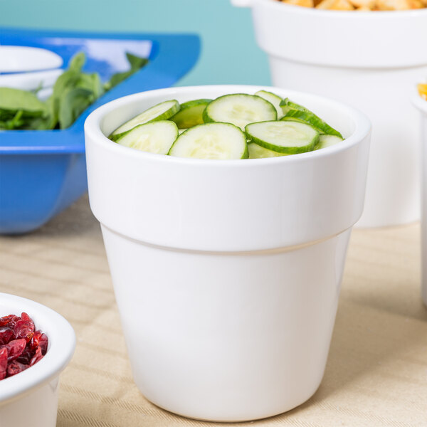 A white Tablecraft round condiment bowl filled with cucumbers.