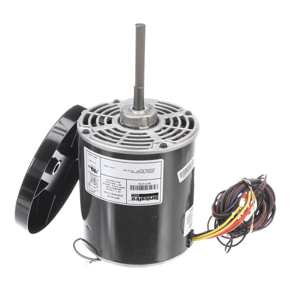 A cylindrical electric motor with a central shaft, attached wiring, and a detached black fan blade cover placed beside it.