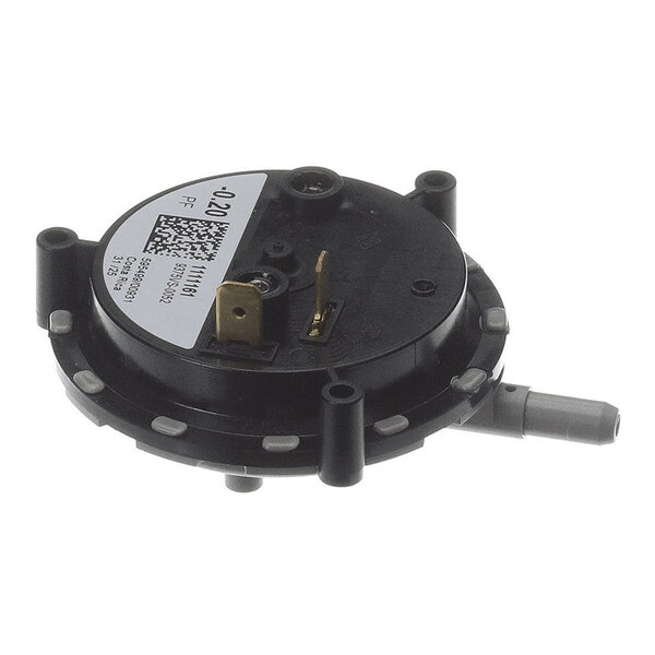 A round black plastic component with a label, electrical terminals, and a protruding gray nozzle.