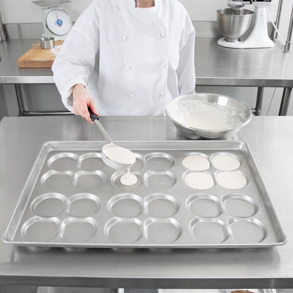 A woman in a white chef's coat pouring white liquid into a Chicago Metallic ePAN.