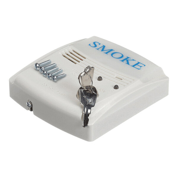 A white device labeled 'SMOKE' with ventilation slots, accompanied by screws and a set of keys placed on top.