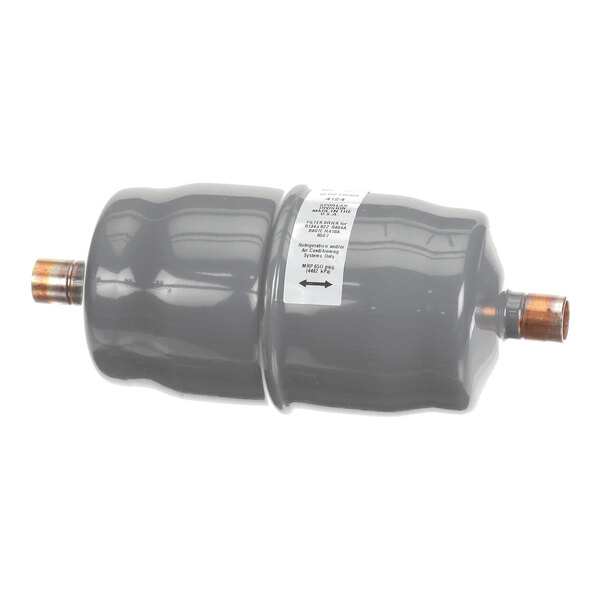A cylindrical, gray metal component with copper fittings on both ends and a white label attached to its side.