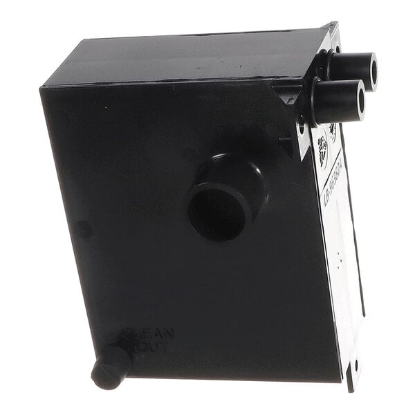A black rectangular plastic component with three cylindrical pipe connections and a label on one side.