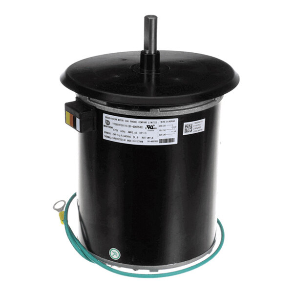 A cylindrical black electric motor with a protruding shaft, a label, and a green grounding wire attached.