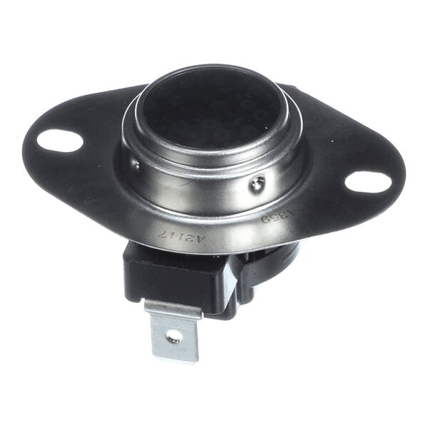 A round metallic component with two mounting holes and an attached black plastic electrical connector with metal terminals.