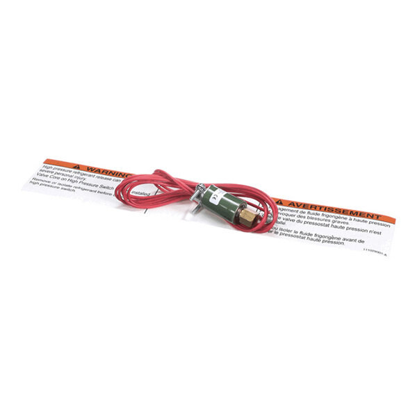 A small electronic component with red wires attached, placed on top of a warning label.