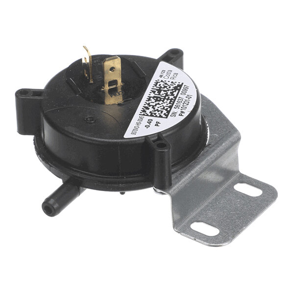 A round black plastic component with two metal terminals, two hose connectors, and a metal mounting bracket.