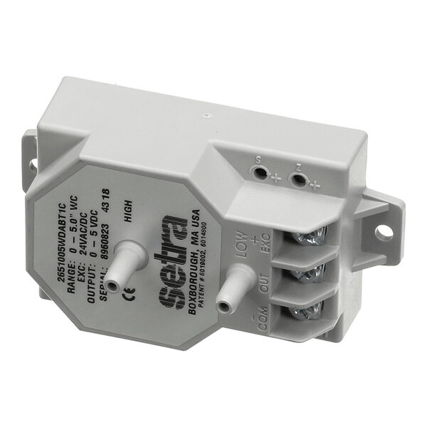 A gray rectangular electronic sensor device with two protruding nozzles, labeled connection terminals, and printed technical specifications on its surface.