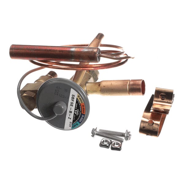 A collection of metal components including copper tubing, a round dial-like part with a label, a coiled tube, a clamp, and screws.